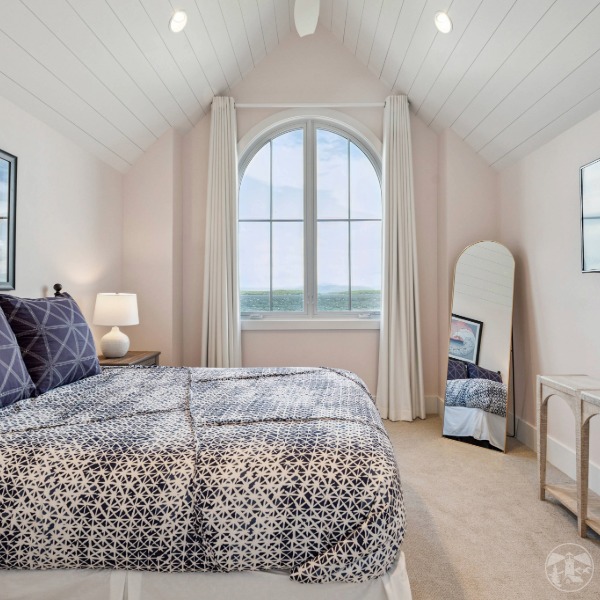 Curved lake house windows brighten upstairs bedroom at Lakeside Legacy luxury remodel